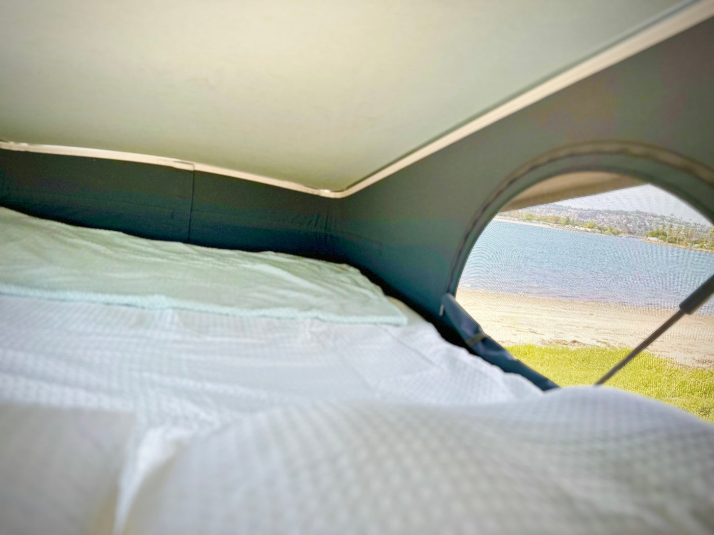  showcasing its pop-top roof and mesh screen door.|RV rental interior: Man interacts with a compact camper van kitchen featuring a sink — photo 8