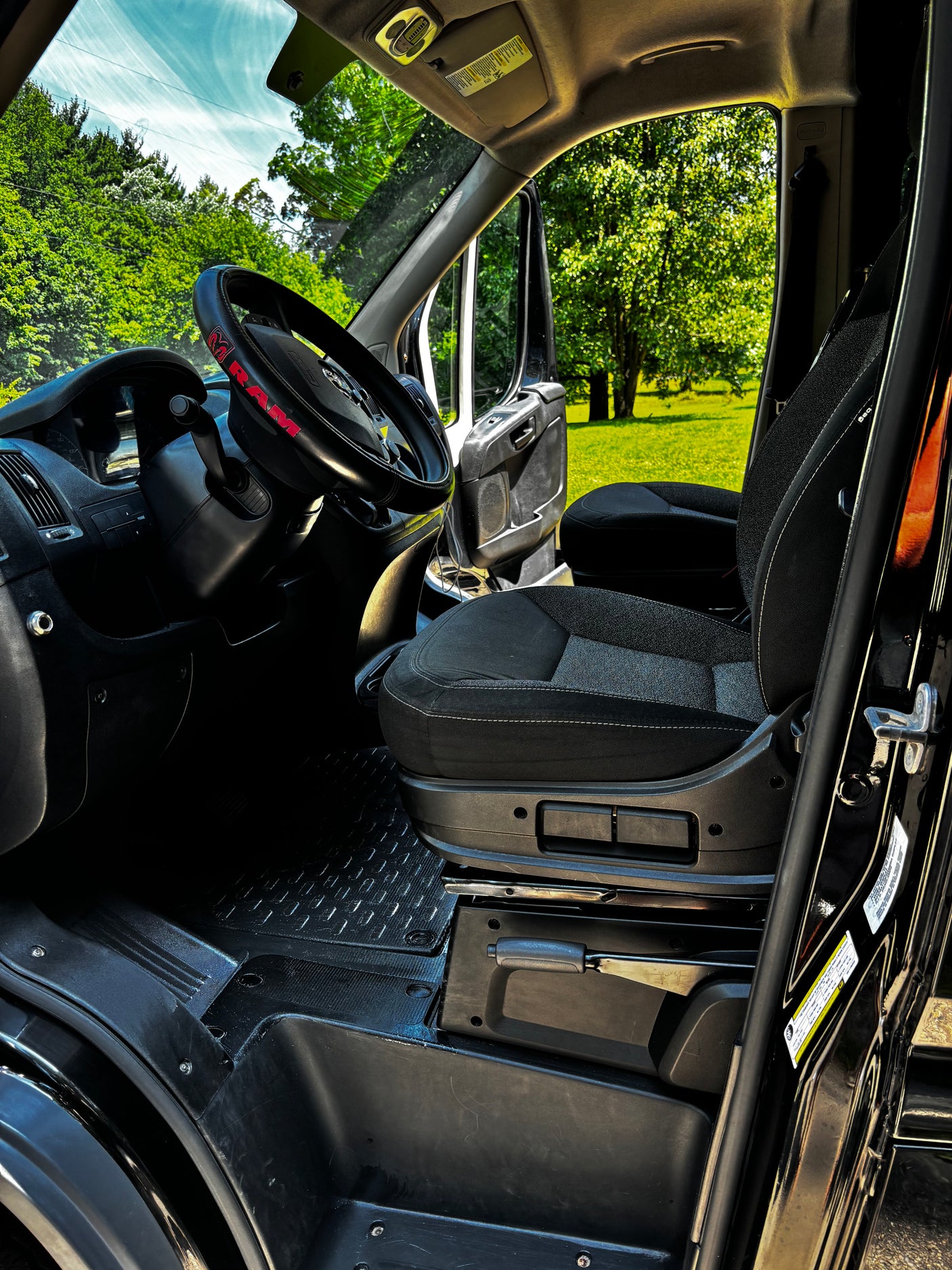 Spacious van interior with driver's seat & open door to nature, ideal for your RV rental.