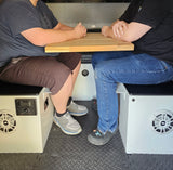 RV rental interior: Two people at a compact table with integrated stereo, ideal for travel and adventure.