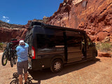 Exploring desert trails! An RV rental with bikes ready for adventure, parked against vast red rock formations.