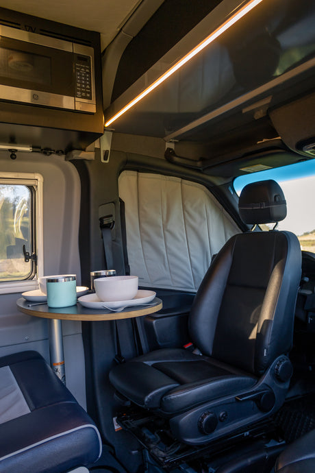 Explore this RV rental's well-equipped interior: a GE microwave, dining area with full place settings, and comfortable seating.