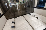 RV rental comfort: interior features plush, quilted seating that converts to beds, glossy wood accents, & window views.