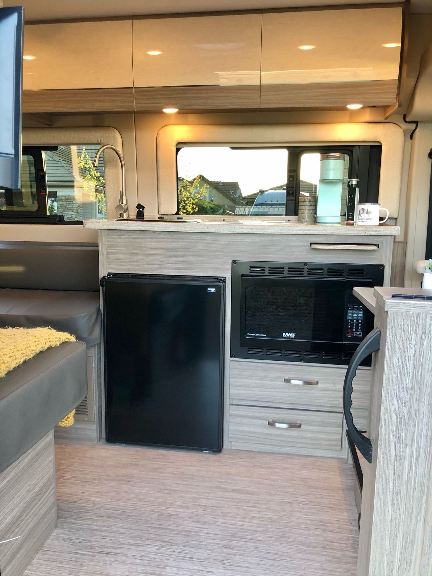Modern RV rental interior: kitchen with sink, microwave, fridge, and cozy seating. — photo 3