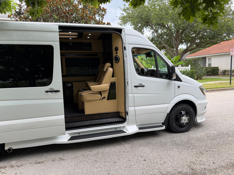 Luxurious white Mercedes Sprinter van RV rental, side door open showing custom tan interior seating and running boards. — photo 6
