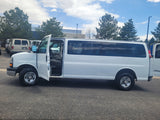 White extended passenger van with open door, parked on asphalt. Similar to vehicles in an rv rental fleet, ready for travel.