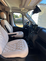 Interior of an RV rental, highlighting plush white quilted seats, dashboard, and steering wheel area.