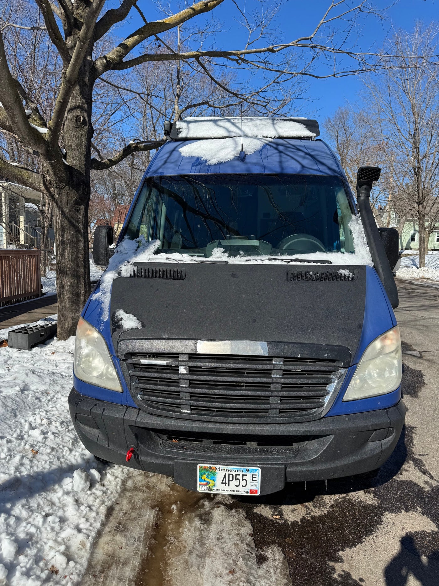 Blue Sprinter rv rental van, partially snow-covered, parked on a Minnesota street. Sunny winter day with bare trees. — photo 9