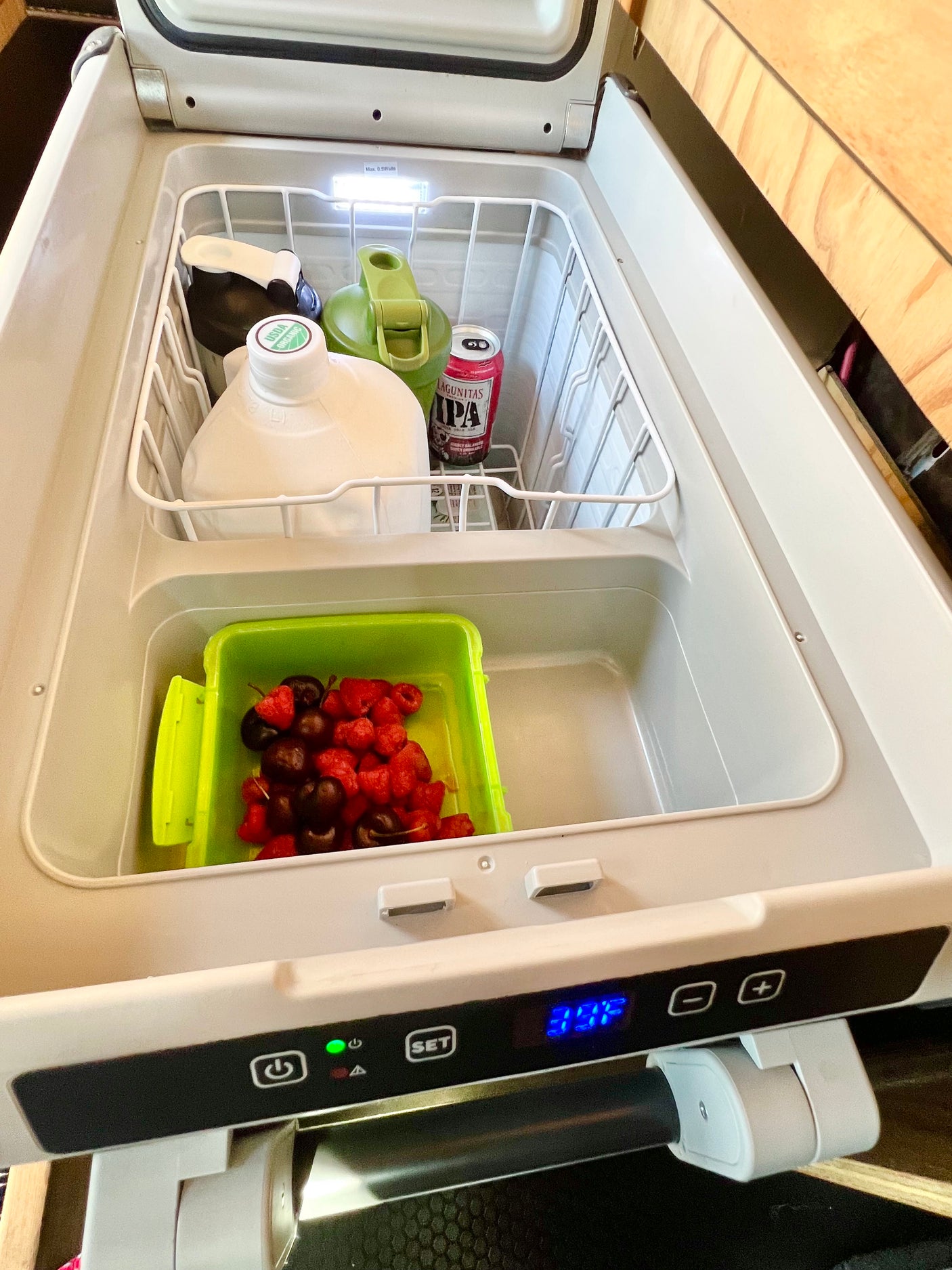 Inside an rv rental's portable fridge, stocked with drinks, organic milk, berries, & beer. Cooling at 3°F for your road trip.