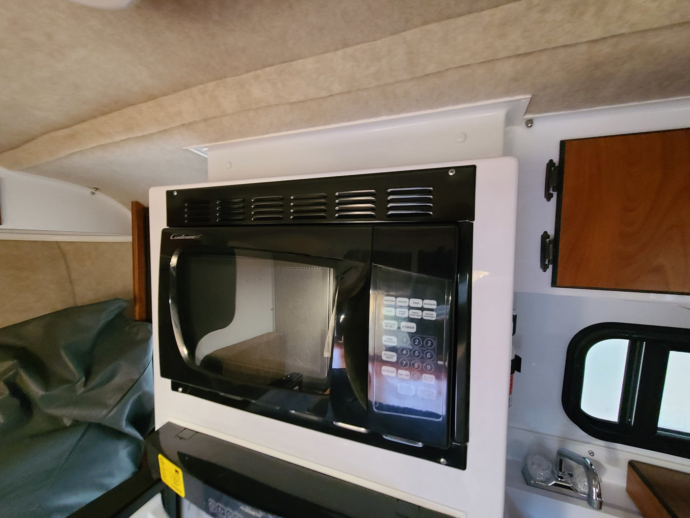 This RV rental features a compact kitchen with a built-in Contoure microwave, perfect for on-the-go meals and travel.
