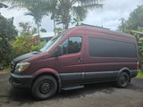 Burgundy Mercedes Sprinter camper van in a lush setting, ideal for an RV rental adventure.