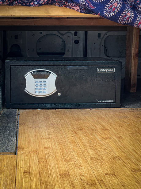 An essential for RV rental security: a black Honeywell digital safe with keypad, mounted on bamboo flooring in a van.