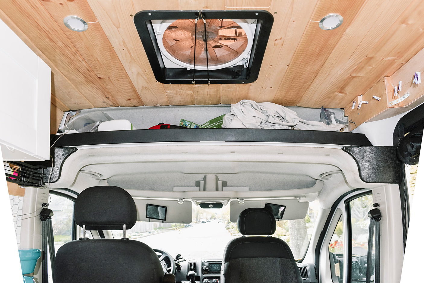 Interior view of an RV rental: wood ceiling with fan & lights, plus front cabin & clever overhead storage.