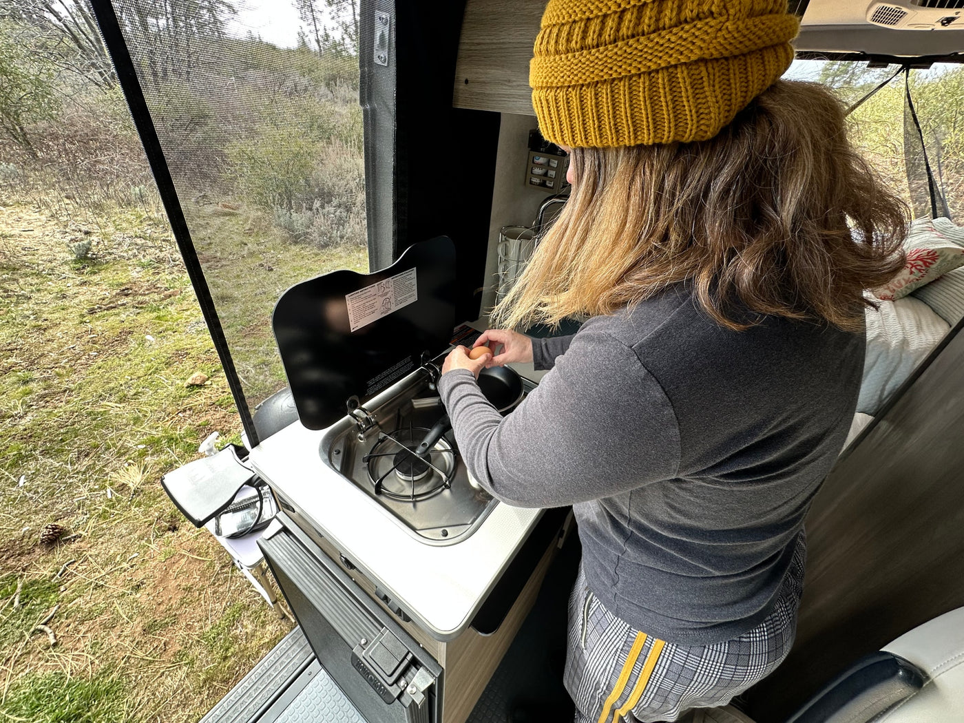  under a blue sky.|Inside an RV rental: a man operates the compact kitchen — photo 12
