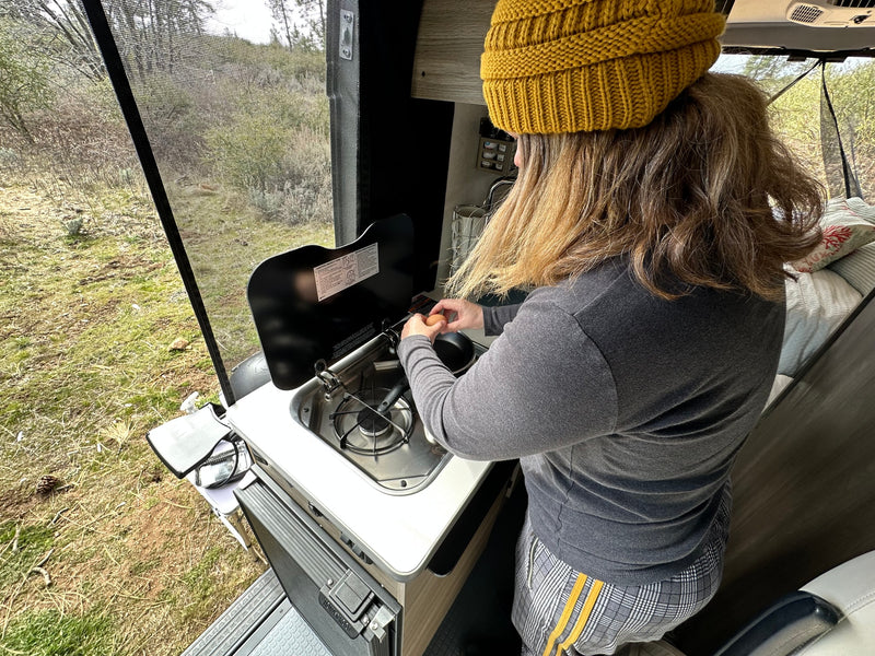  under a blue sky.|Inside an RV rental: a man operates the compact kitchen — photo 12