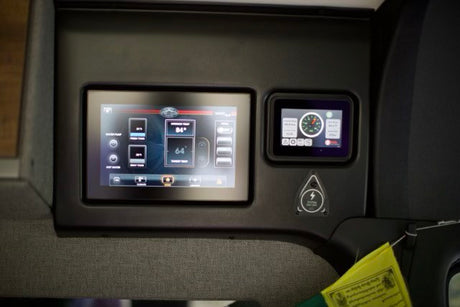 Inside an RV rental: a control panel with dual screens displaying fresh/gray tank levels, interior temp, and battery data.