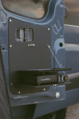RV rental feature: A CookMax portable gas stove resting on a flip-down table mounted inside a van door, ready for camping meals.