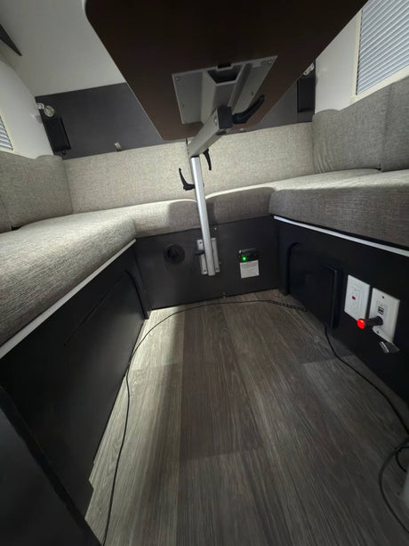 Cozy RV rental interior featuring a U-shaped dinette with gray cushions, adjustable table, wood-look floor, and power outlets.