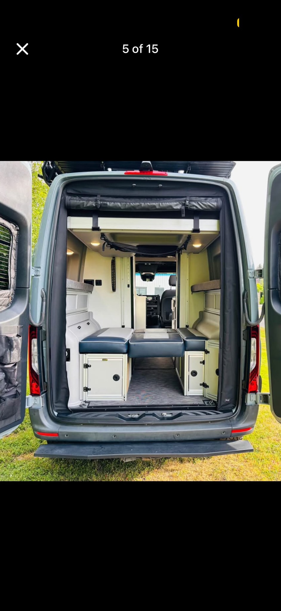This rv rental shows a custom camper van interior from the rear, featuring modular seating, storage units, and a convertible bed. — photo 12