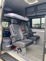 RV rental interior featuring flexible passenger seats, overhead bunk bed, storage, and a marina view. Ideal for travelers.