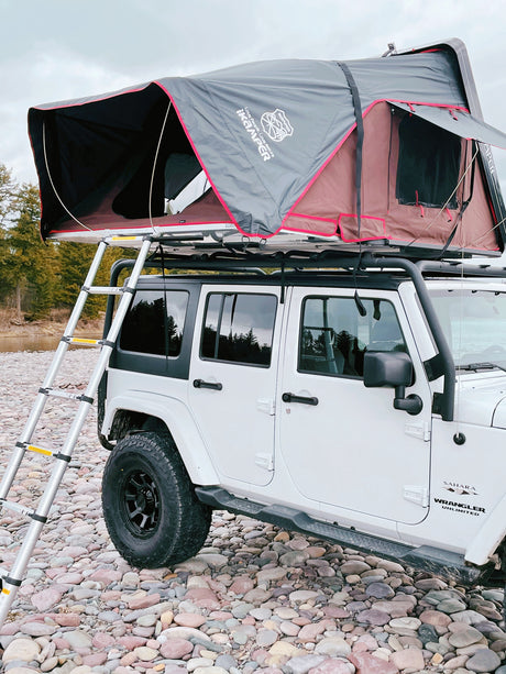 White Jeep Wrangler, iKamper rooftop tent deployed, ladder to riverbed. A unique RV rental for overlanding.