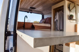 Inside a sleek RV rental: modern kitchenette, comfy bed, and built-in storage. Perfect for adventure travel.