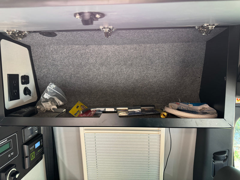 An RV rental's overhead cabinet displaying tools, hoses, and an electrical control panel with a solar charge controller. — photo 19