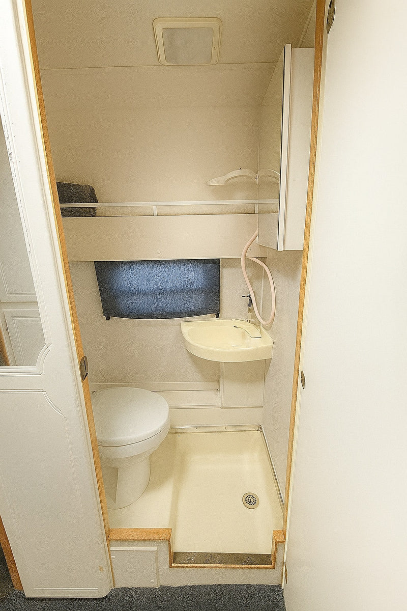 RV rental: Compact onboard bathroom with toilet, small sink/shower combo, and ceiling light. Efficient use of space. — photo 6