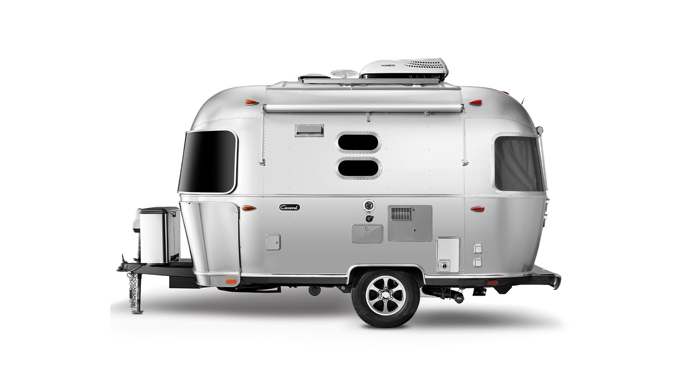 A modern, silver recreational travel trailer, often sought for rv rental, featuring distinctive oval windows and roof AC.