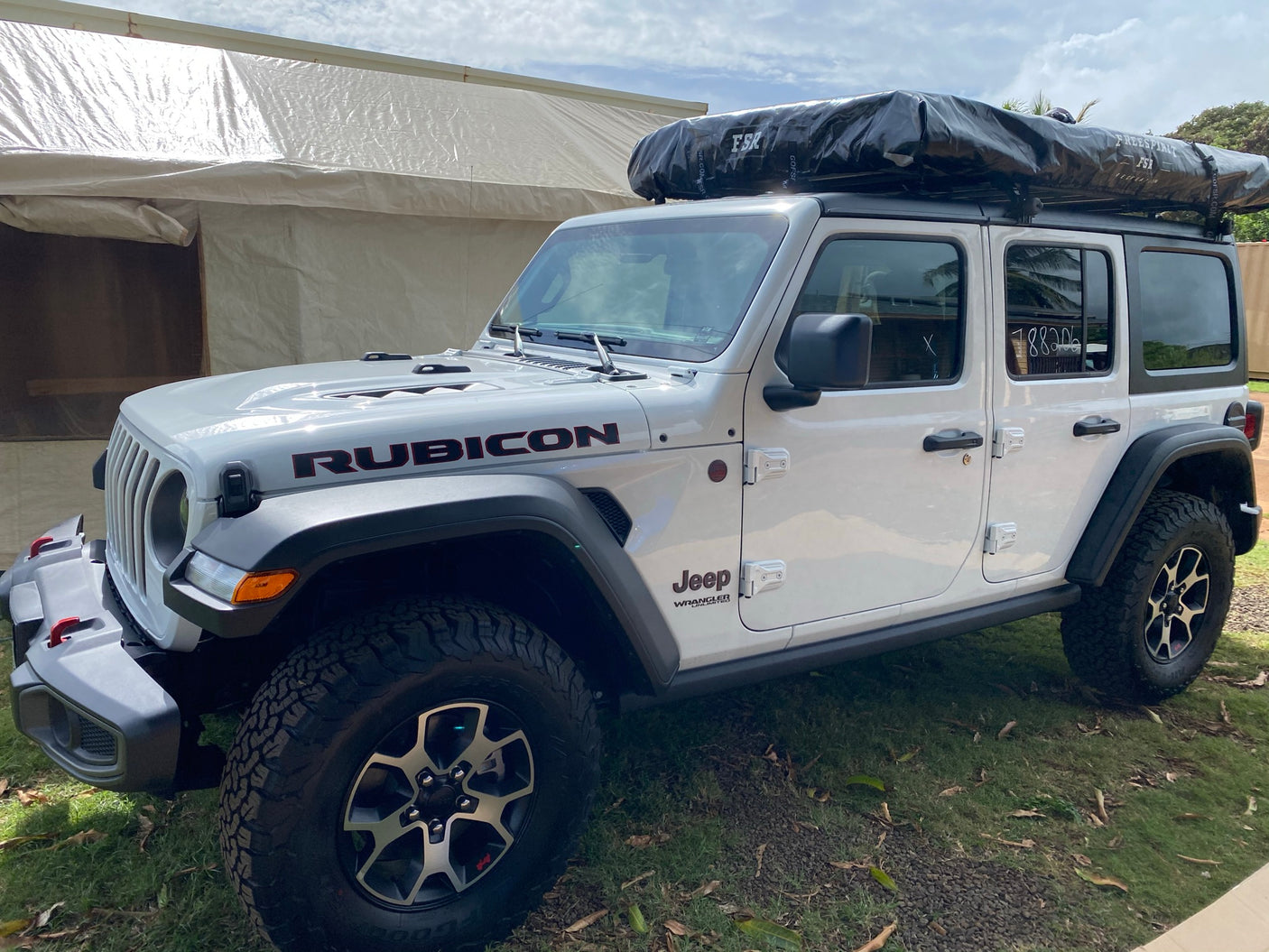 White Jeep Wrangler Rubicon with rooftop tent, ideal for an RV rental adventure.