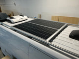 Solar panels and a Dometic AC unit are mounted on the roof of a white RV rental van, prepared for comfortable off-grid travel.