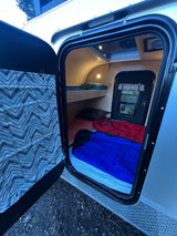 Cozy RV rental interior: bunk beds and sleeping bags ready for camping and outdoor adventures.