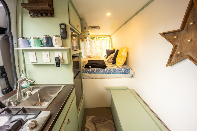 Cozy RV rental interior featuring a compact kitchen, comfortable bed area, and bench seating, perfect for mobile travel. — photo 3