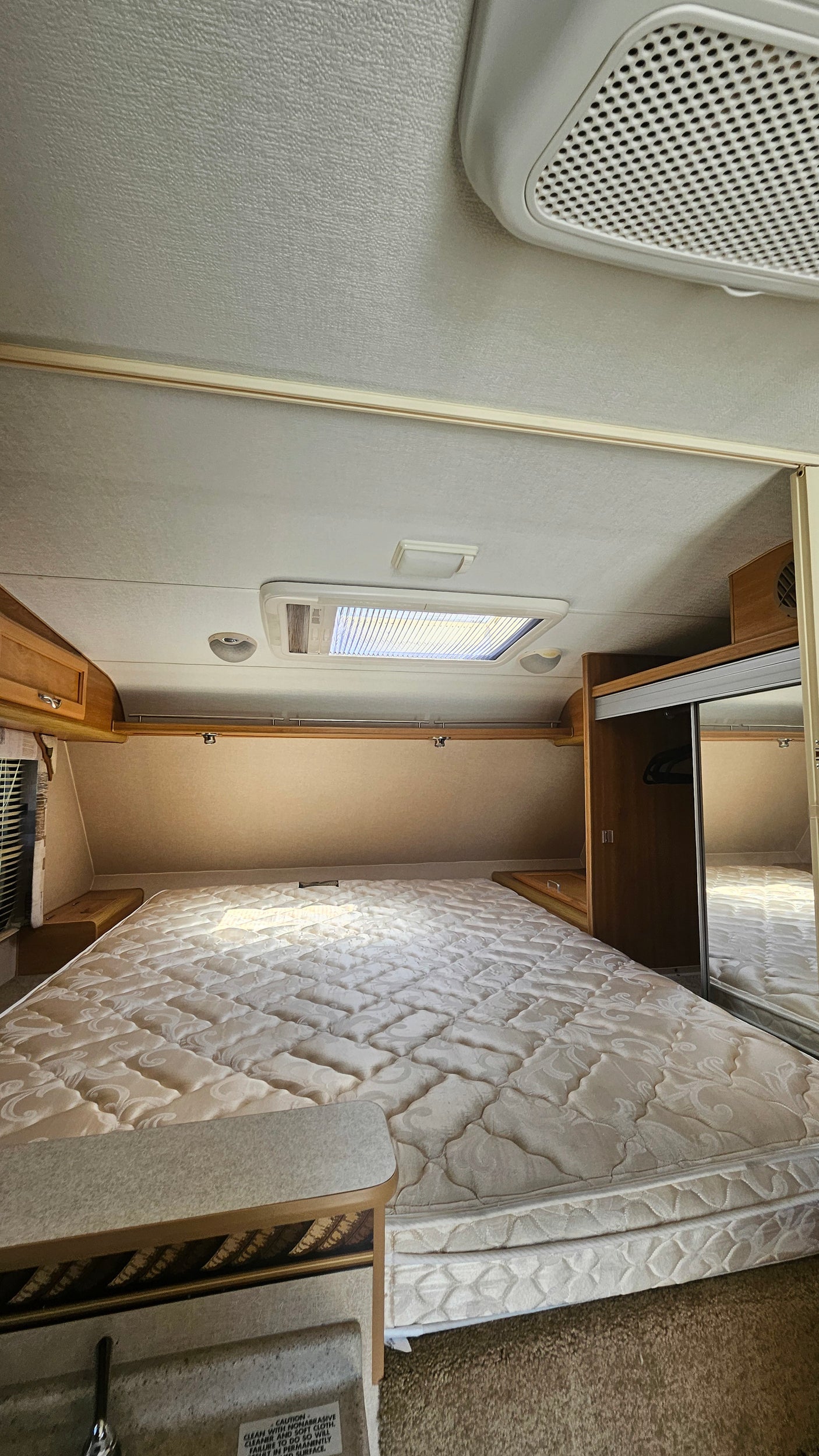 Inside an RV rental: a cozy bedroom features a large mattress, skylight, and built-in storage for comfortable travel.