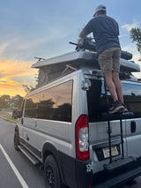 Adjusting the Yakima roof rack on an RV rental pop-top camper van at sunset, preparing for a memorable adventure.