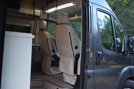 Inside an RV rental: Comfortable captain's chairs in a modern camper van's front cabin.