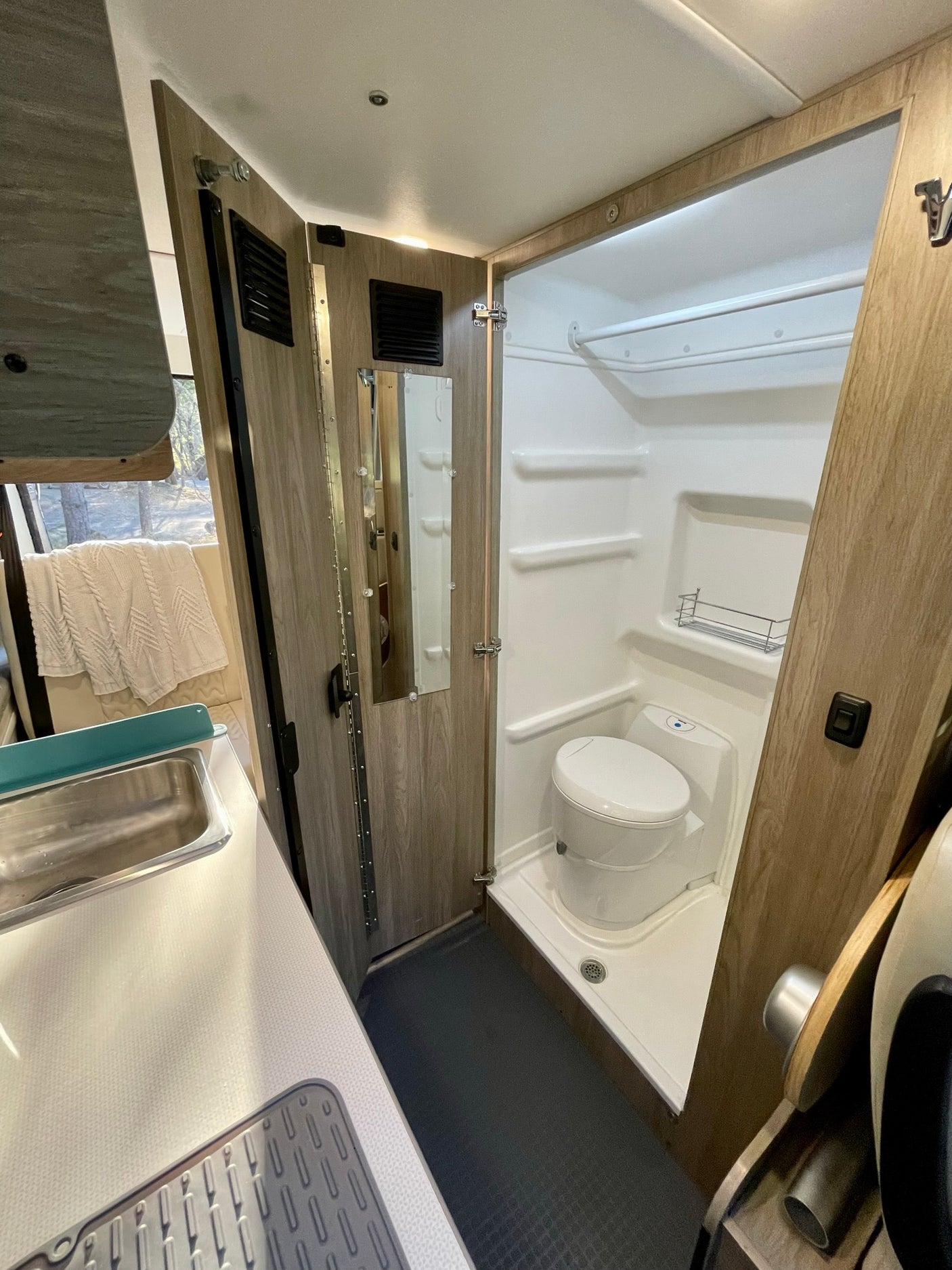 Compact RV rental interior: integrated bathroom with toilet & shower, plus a small kitchen sink. Ideal for travel.