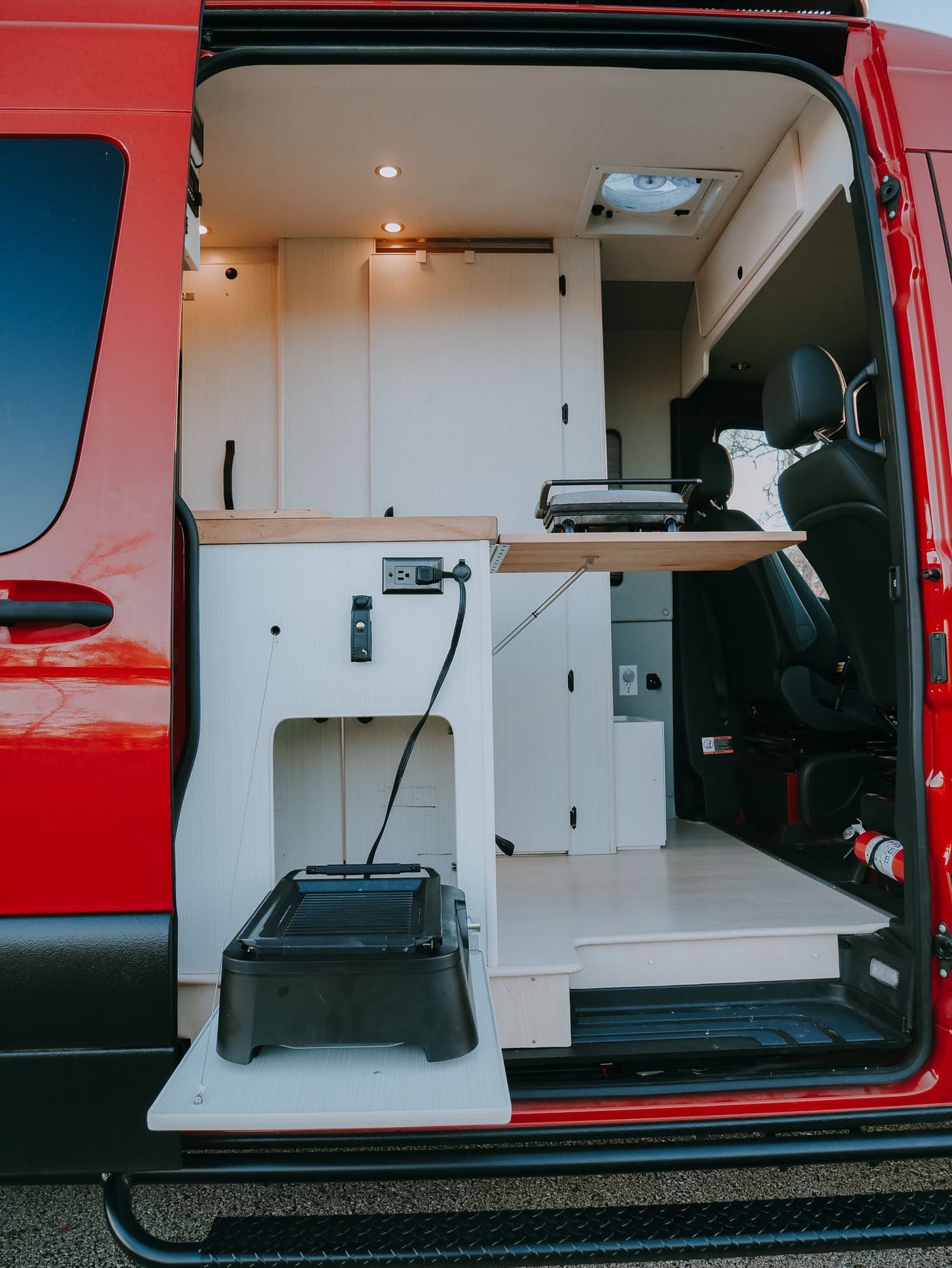A bright, functional RV rental interior, featuring a pull-out kitchen with grill and power outlets, perfect for mobile adventures.