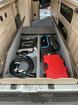 RV rental storage: Essential utility gear like power cord, hose, and tools organized in a floor compartment.