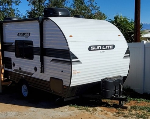 White Sun Lite Classic travel trailer, ideal for an rv rental, showcasing its side profile, awning, and front propane cover. — photo 3