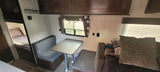 Inside an RV rental: view of dinette, overhead cabinets, bunk beds, and lounge seating.