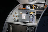 Compact RV rental kitchen with stove, sink, microwave & fridge. Perfect for camping adventures and road trips.