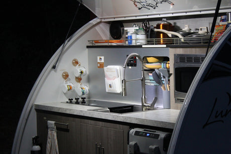 Compact RV rental kitchen with stove, sink, microwave & fridge. Perfect for camping adventures and road trips.