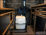 RV rental: Portable toilet stored on pull-out slide between custom black and wood cabinets, optimizing interior.