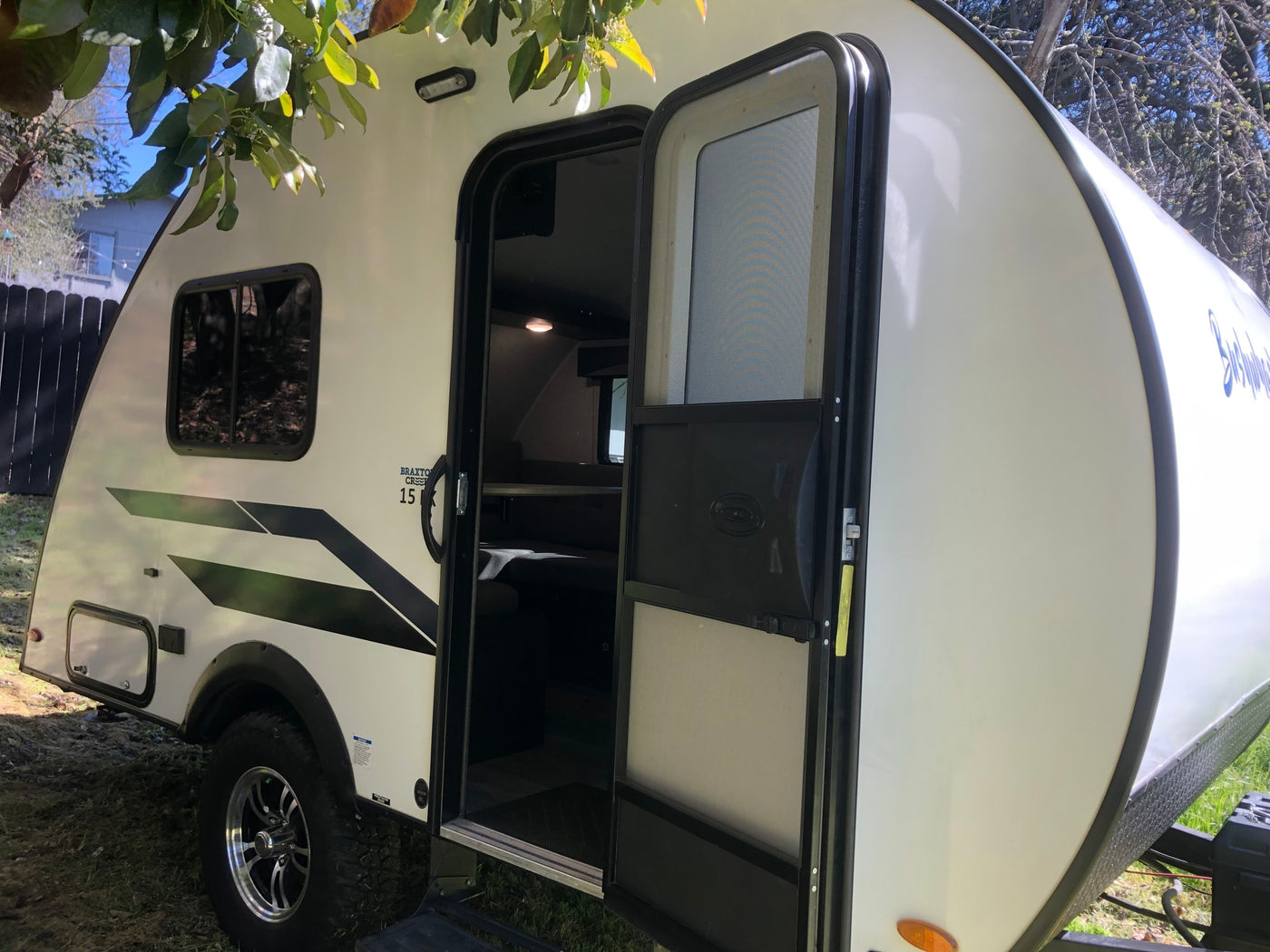  a compact travel trailer parked outdoors with its door open — photo 3