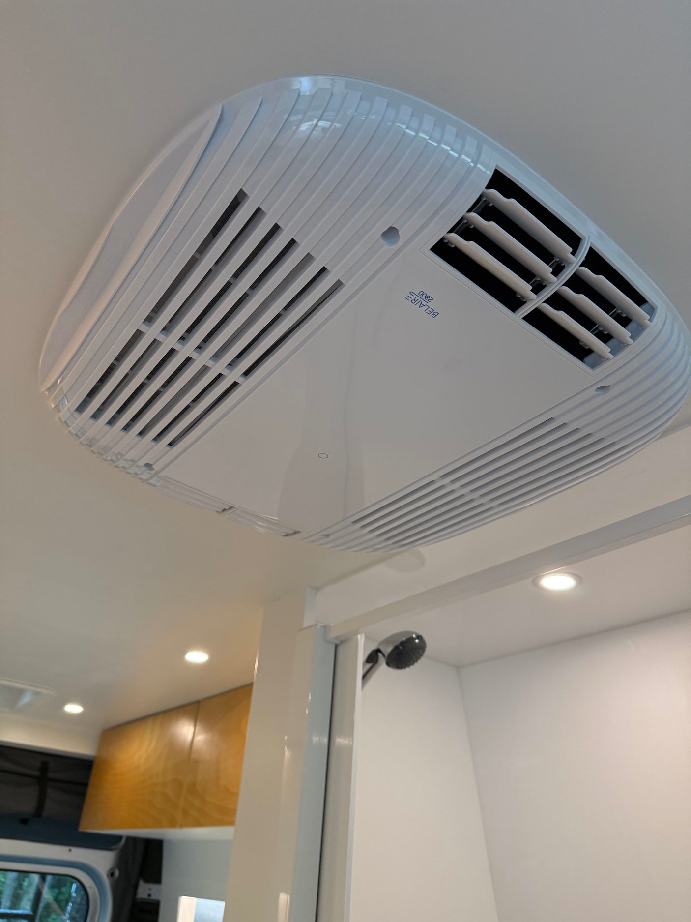 RV rental interior featuring a white ceiling-mounted AC unit (Belair 2800), recessed lighting, and a modern shower setup.
