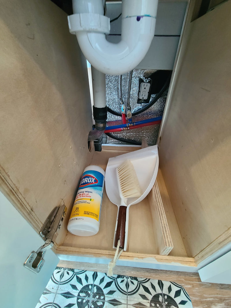 RV rental: Compact under-sink cabinet storage with plumbing, electrical outlet, Clorox wipes, and dustpan. — photo 17