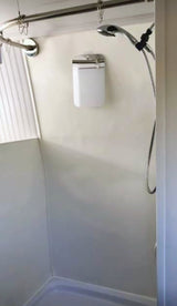 An RV rental shower featuring a compact design, curved curtain rod, handheld showerhead, and a wall-mounted dispenser.