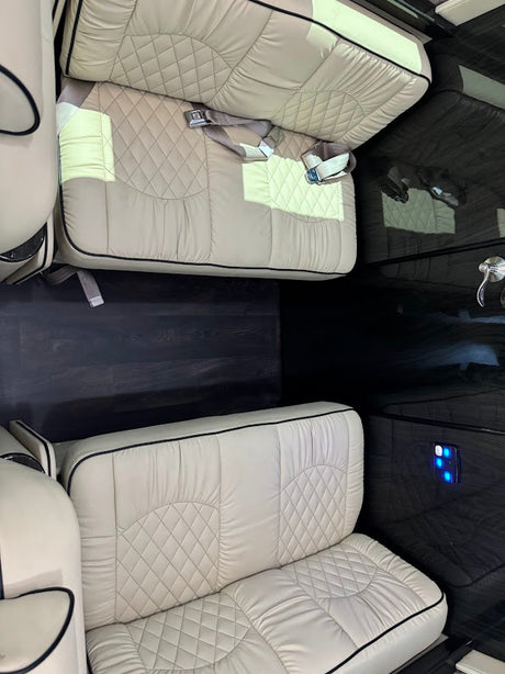 View inside a premium RV rental, featuring luxurious cream quilted seating, dark wood-look flooring, and sleek interior design.