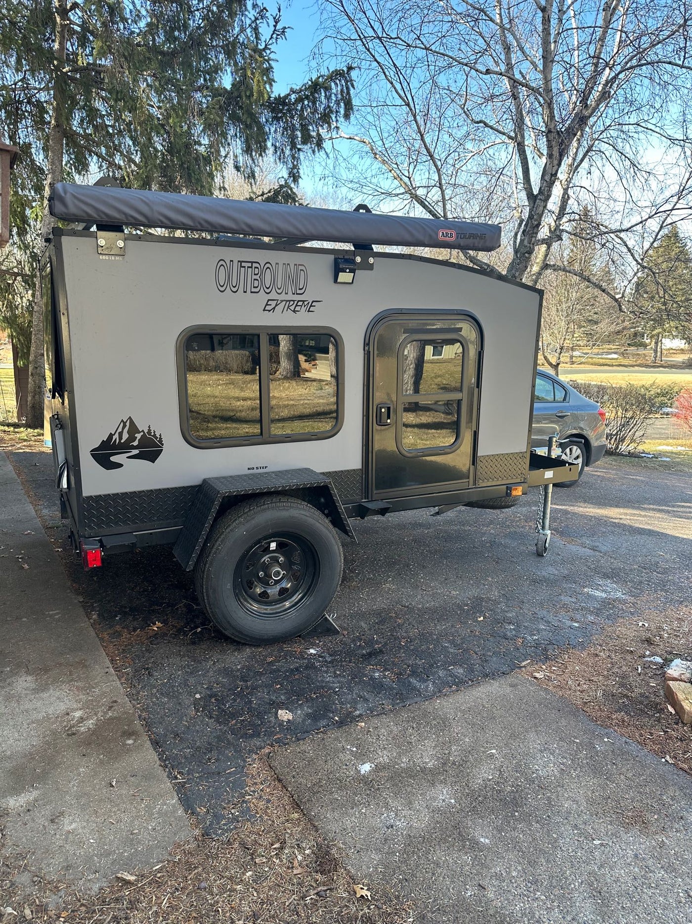  parked on a suburban street. Ideal for an RV rental getaway.|A rugged Outbound Extreme camper trailer