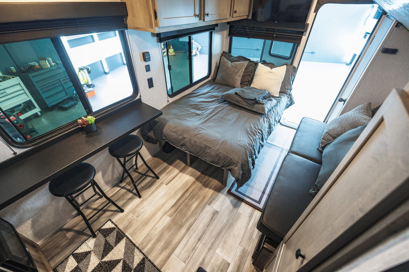 Cozy RV rental interior featuring a queen bed, dining bar with stools, and comfortable lounge area. Perfect for your next adventure. — photo 16